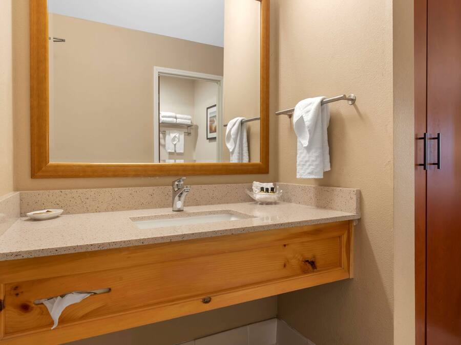 A bathroom with a wooden vanity, a sink, a mirror, and a towel rack.