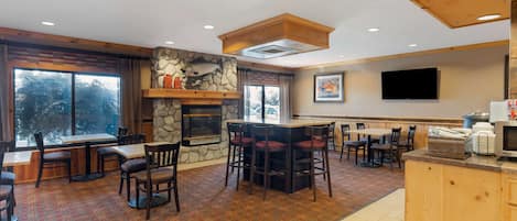 A restaurant with a stone fireplace, wooden bar, and outdoor seating.