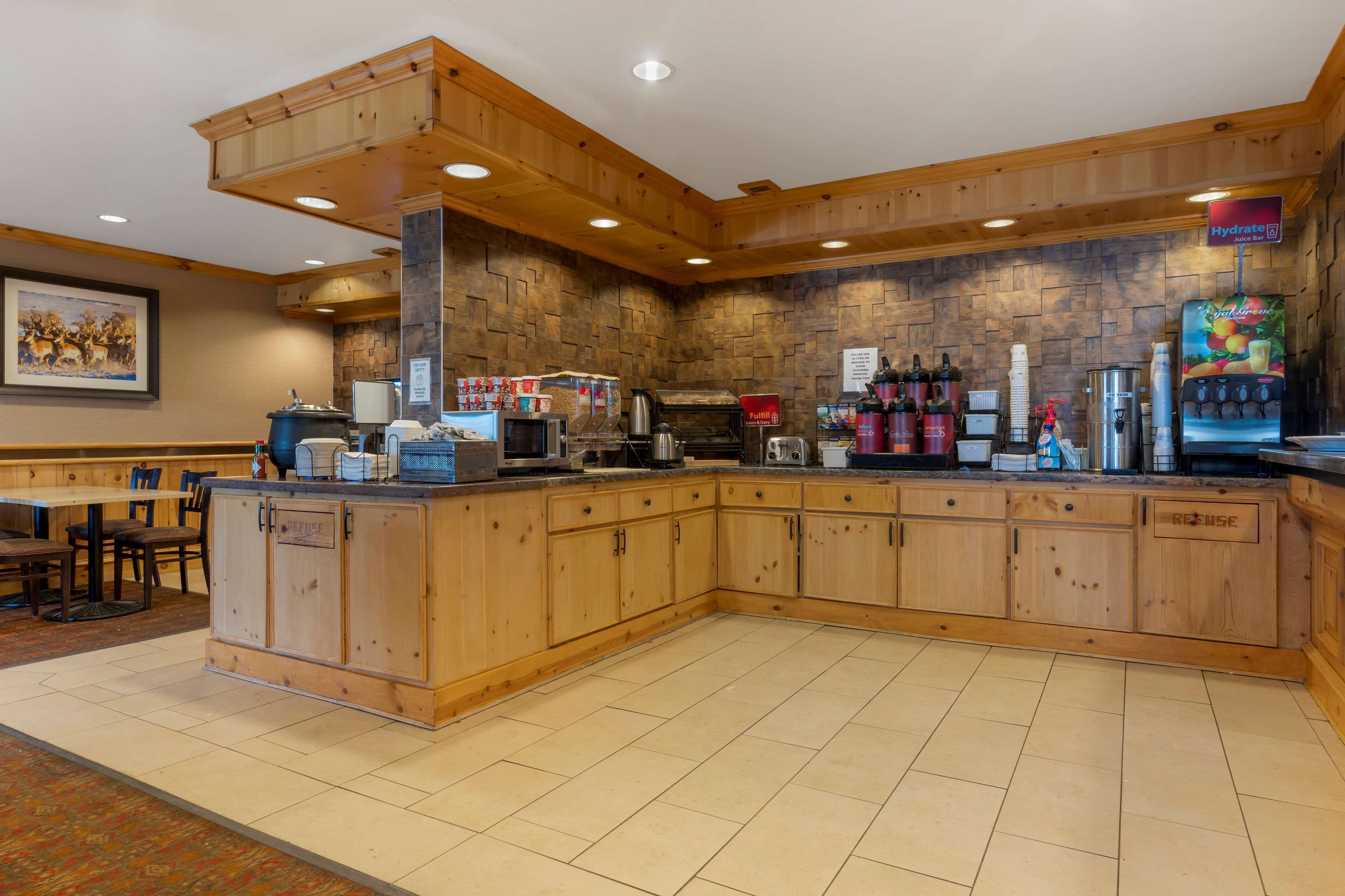 A kitchen area with wooden cabinets, a coffee station, and a stone wall backdrop.