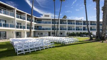 A hotel with multiple balconies and a lawn area with white chairs arranged for an event.