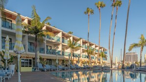 Un hôtel doté d’une piscine, de chaises longues et de palmiers.