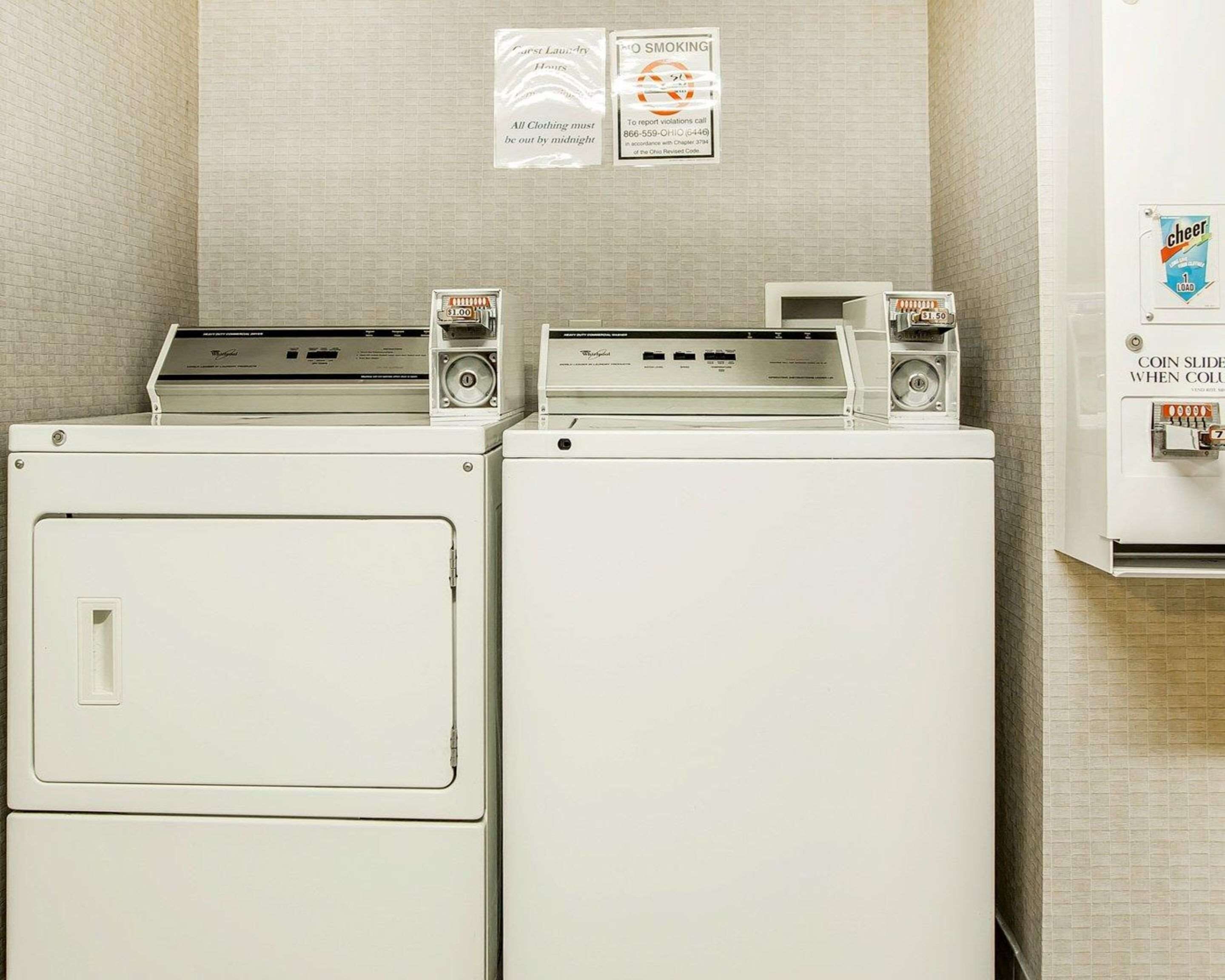 A laundromat with two washers and dryers, a coin-operated dryer, and a sign indicating a smoking area.