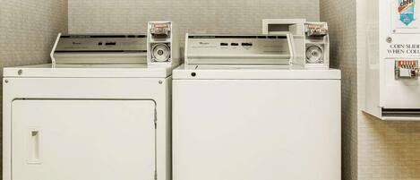A laundromat with two washers and dryers, a coin-operated dryer, and a sign indicating a smoking area.