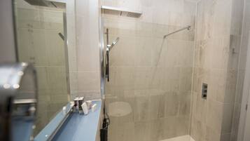 A modern bathroom with a glass-enclosed shower, a blue sink, and a large mirror.