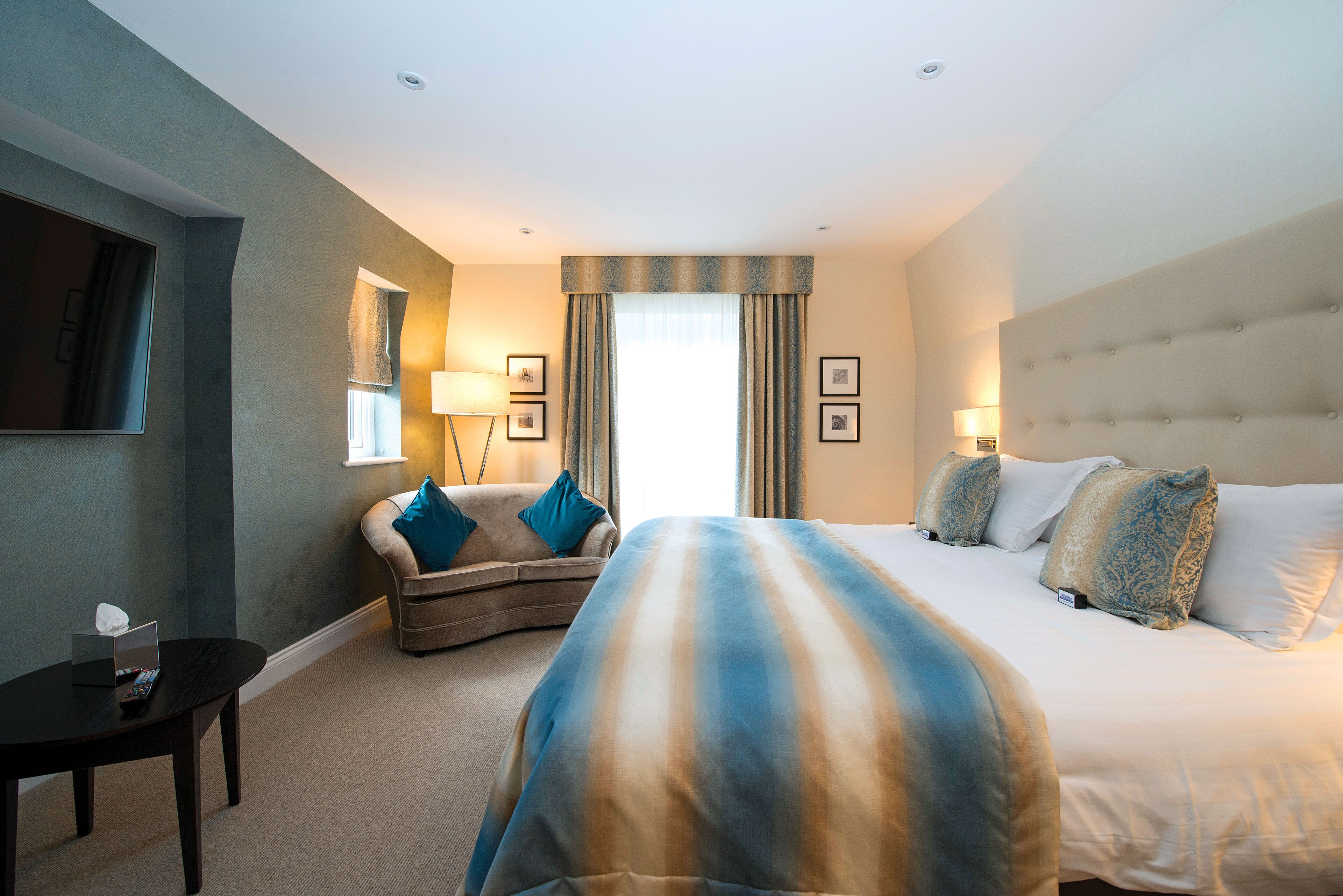A hotel room with a large bed, a sofa, a small table, and a TV.