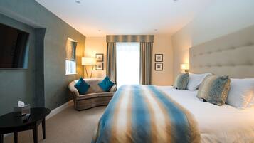 A hotel room with a large bed, a sofa, a small table, and a TV.