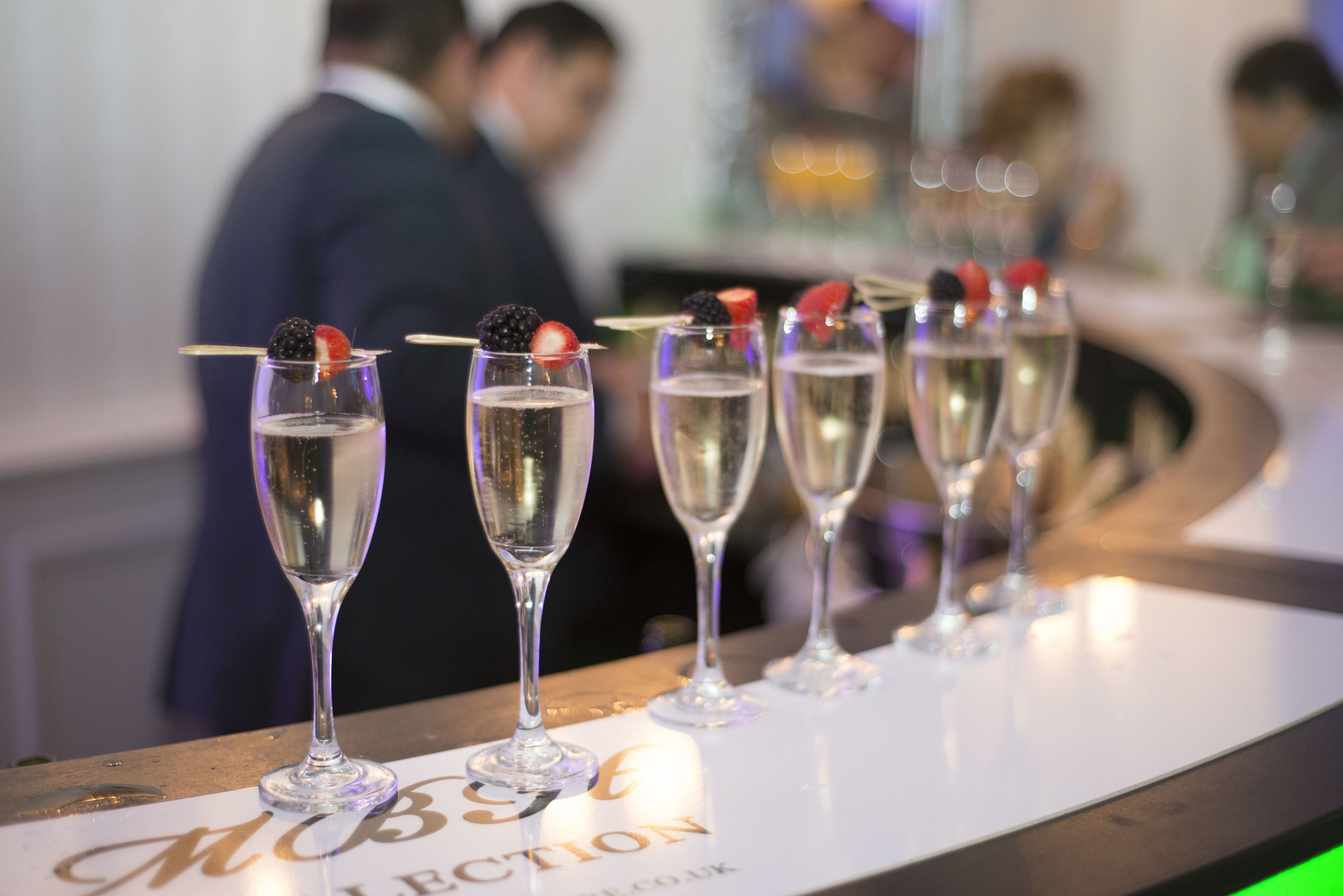 Een bar met champagneglazen op een toonbank, elk voorzien van een fruitdecoratie.