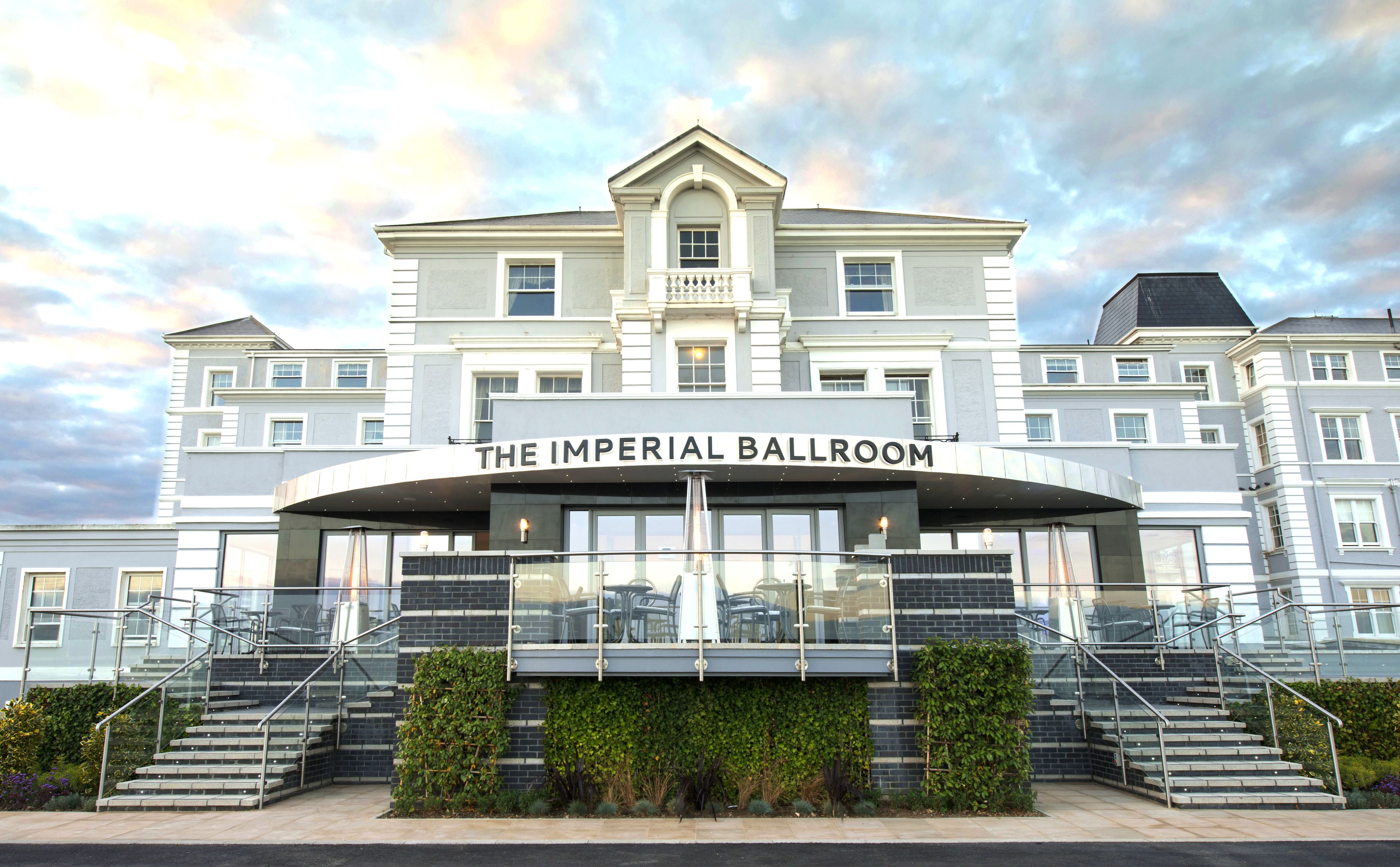 Een hotel genaamd "The Imperial Ballroom" met een statig entree, meerdere verdiepingen en een trap die naar de ingang leidt.