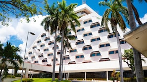 Un hotel moderno con una facciata geometrica, diversi balconi e palme.