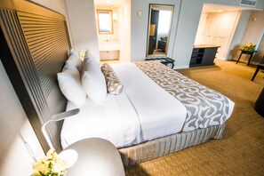 A hotel room with a large bed, a bedside table, a mirror, and a view of the hallway. - Crowne Plaza Managua by IHG (Managua)