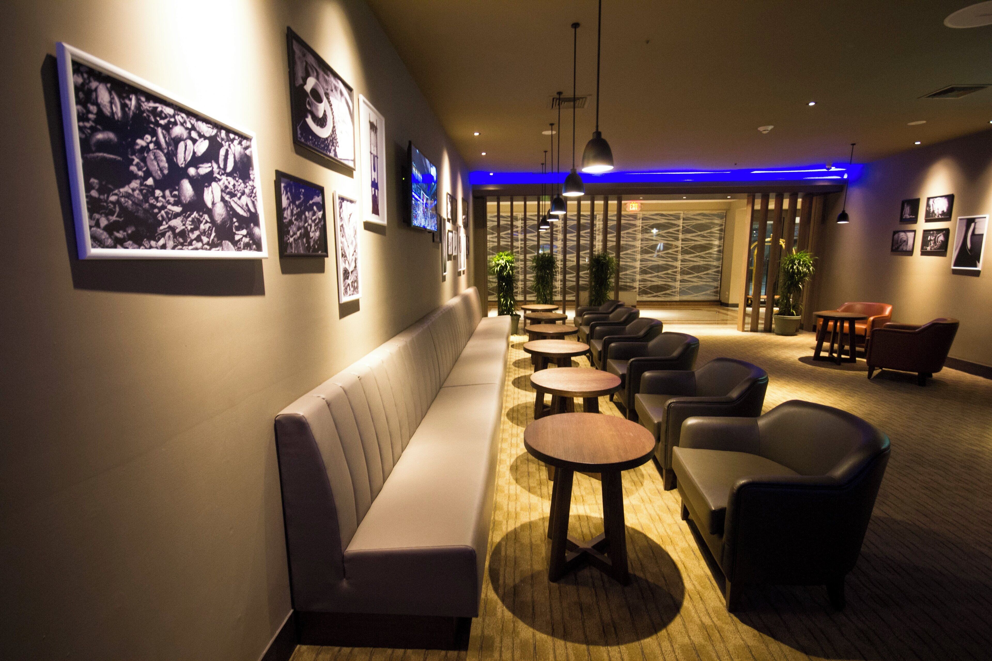 A hotel lobby with a sofa, chairs, tables, and wall art.