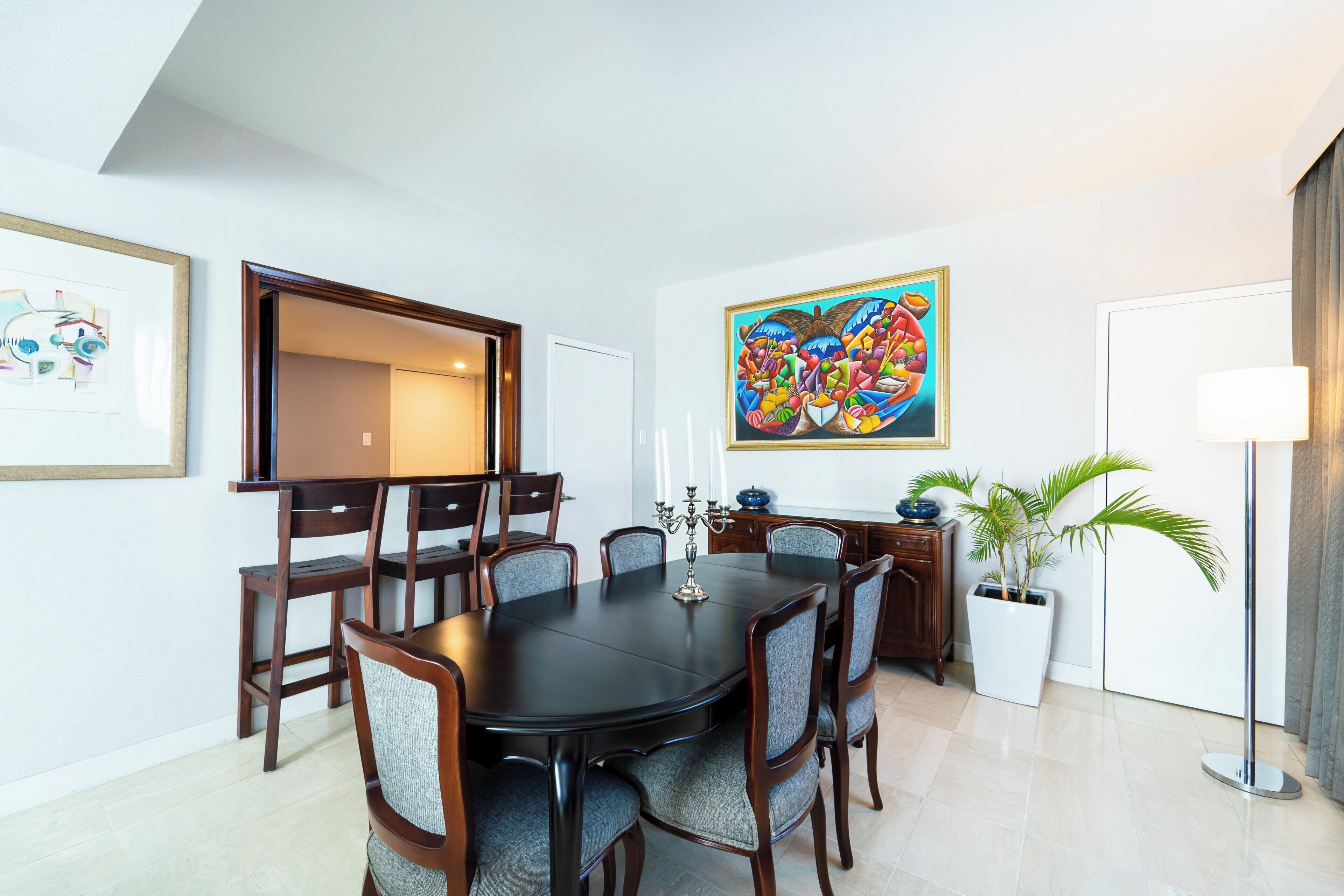 Un coin repas avec une table ronde, six chaises et deux tableaux accrochés aux murs.