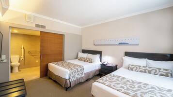 Habitación de hotel con dos camas, una puerta de madera, ducha y una obra de arte colgada en la pared.