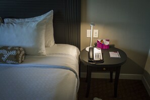 A hotel room with a bed, a bedside table with a telephone, a lamp, and a box of tissues. - Crowne Plaza Managua by IHG (Managua)