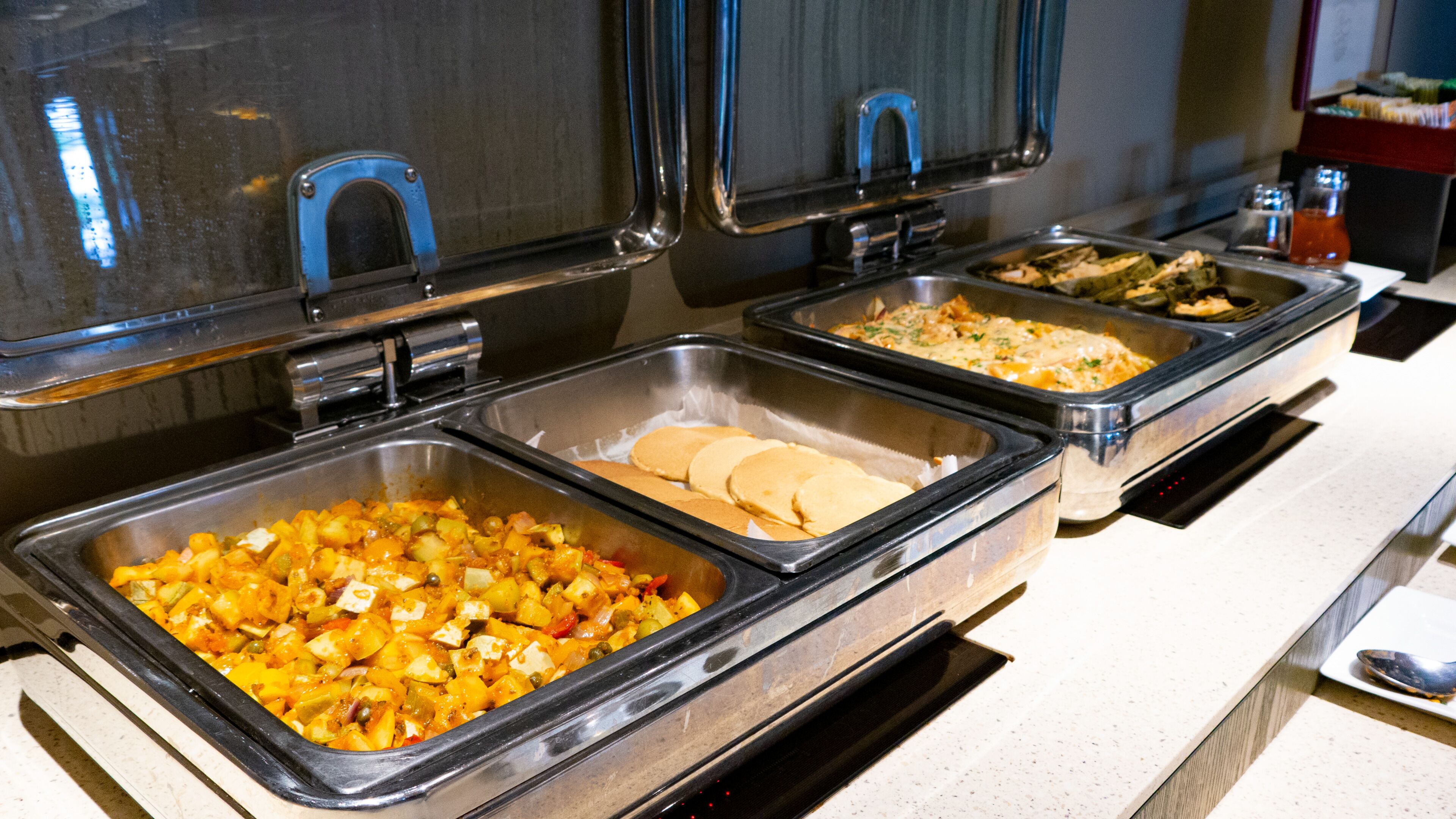 Un buffet proposant une variété de plats, notamment un plat en gratin, une assiette de crêpes et une salade.