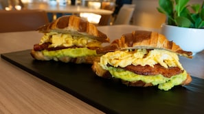 Due panini per la colazione su un piatto rettangolare scuro.