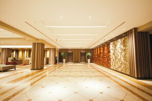A spacious lobby with a tiled floor, a reception desk, seating area, and a decorative wall. - Crowne Plaza Managua by IHG (Managua)