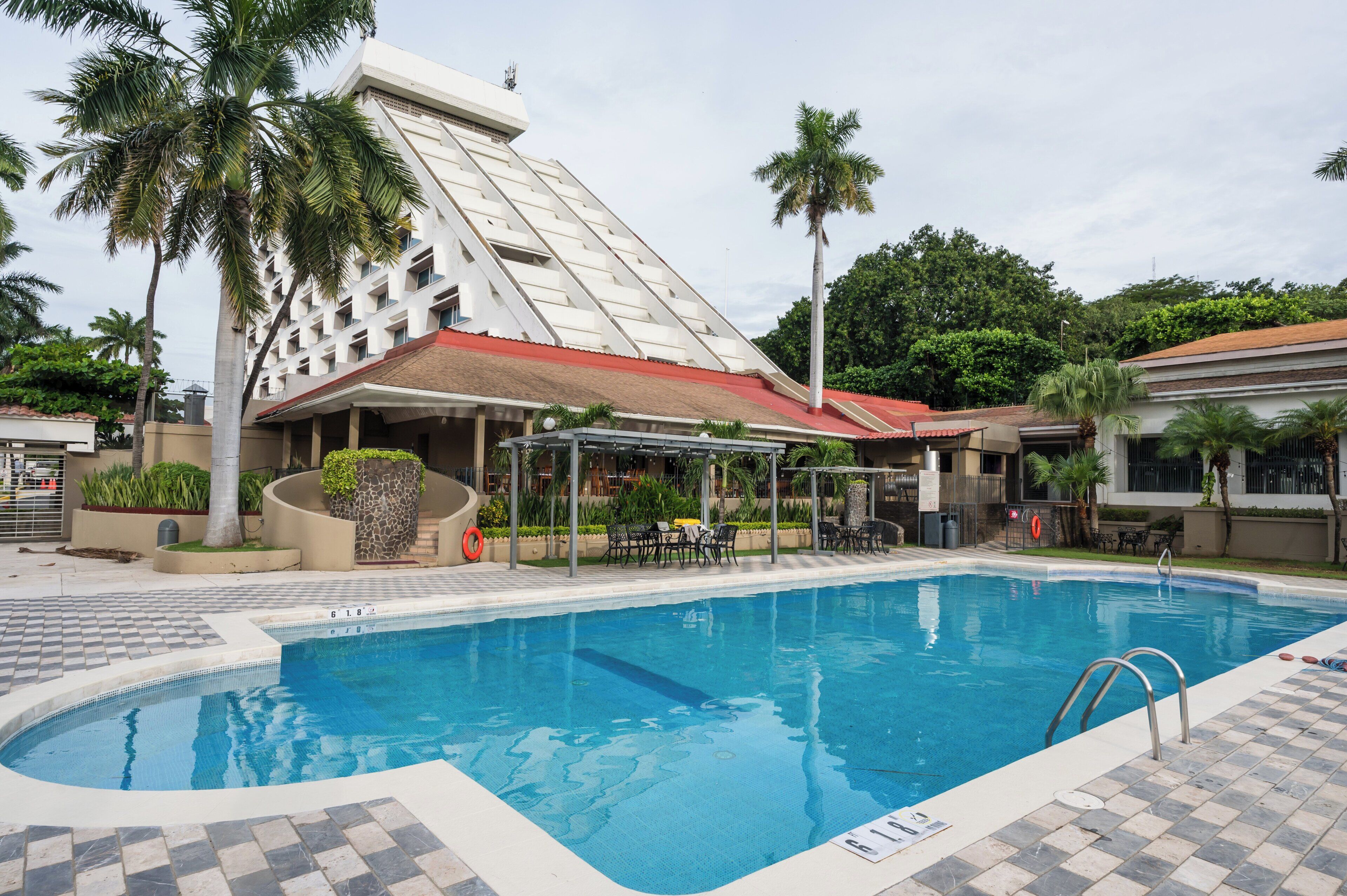 Una piscina al aire libre, sombrillas, sillones reclinables de piscina