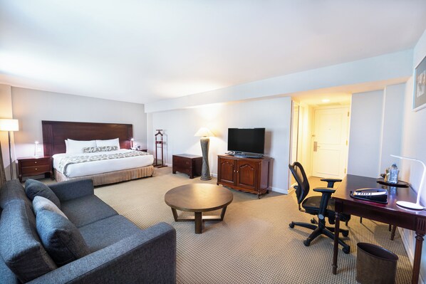 A hotel room with a bed, a sofa, a desk, a chair, a television, and a lamp. - Crowne Plaza Managua by IHG (Managua)