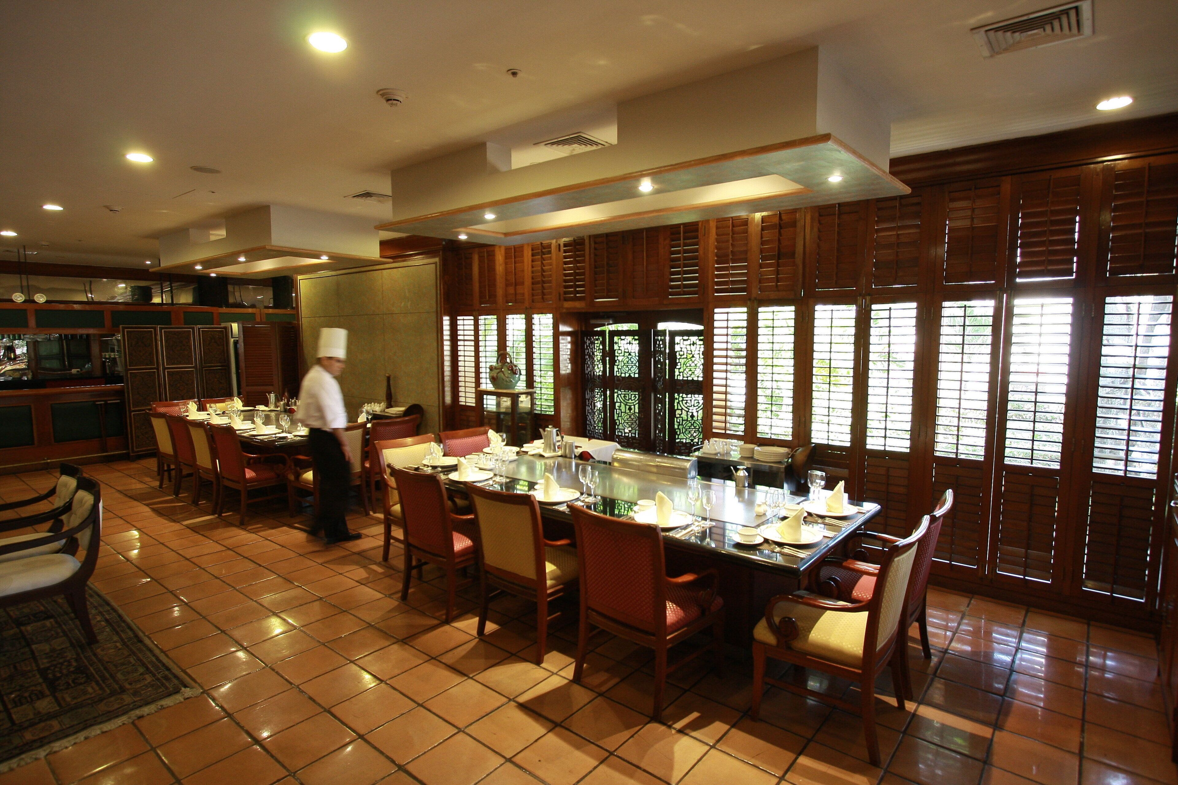 A restaurant with a large dining table set for multiple guests, surrounded by wooden chairs.