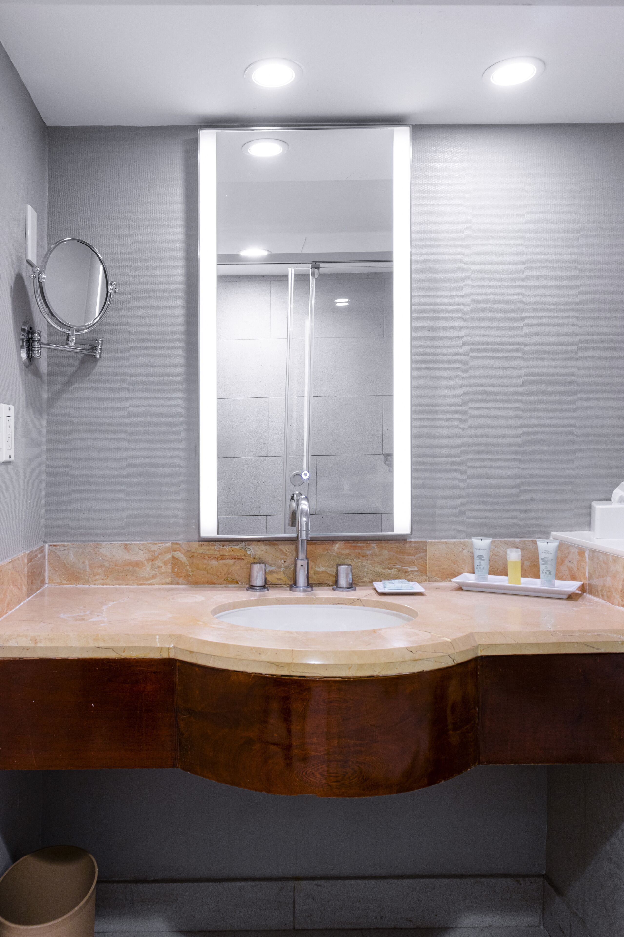 A modern bathroom with a large mirror, a sink, and a shower.