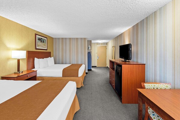 Une chambre d’hôtel avec deux lits, un bureau, une télévision et une armoire.