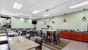 A modern restaurant with multiple dining tables and booths, a kitchen area, and a flat-screen TV mounted on the wall. - Best Western Cascadia Inn (Everett)