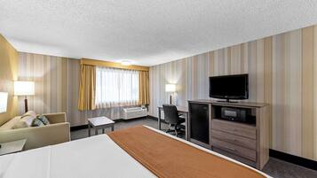 A hotel room with a bed, a desk, a television, and a minibar.