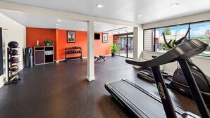 A gym with treadmills, a bench, and a wall-mounted rack of dumbbells. - Best Western Cascadia Inn (Everett)