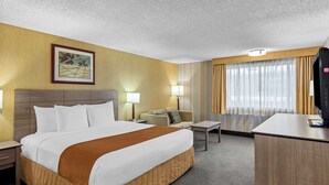 A hotel room with a large bed, a desk, a sofa, and a television. - Best Western Cascadia Inn (Everett)