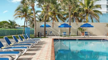 Una piscina al aire libre, sombrillas, sillones reclinables de piscina