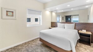 A hotel room with a large bed, a bedside table with a phone, a window, and a framed picture on the wall. - Crystal Beach Suites Miami Oceanfront Hotel (Miami Beach)