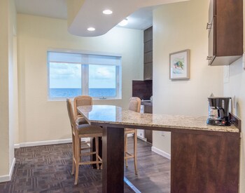 A gym with various exercise machines, mirrors, and a large window. at Crystal Beach Suites Miami Oceanfront Hotel