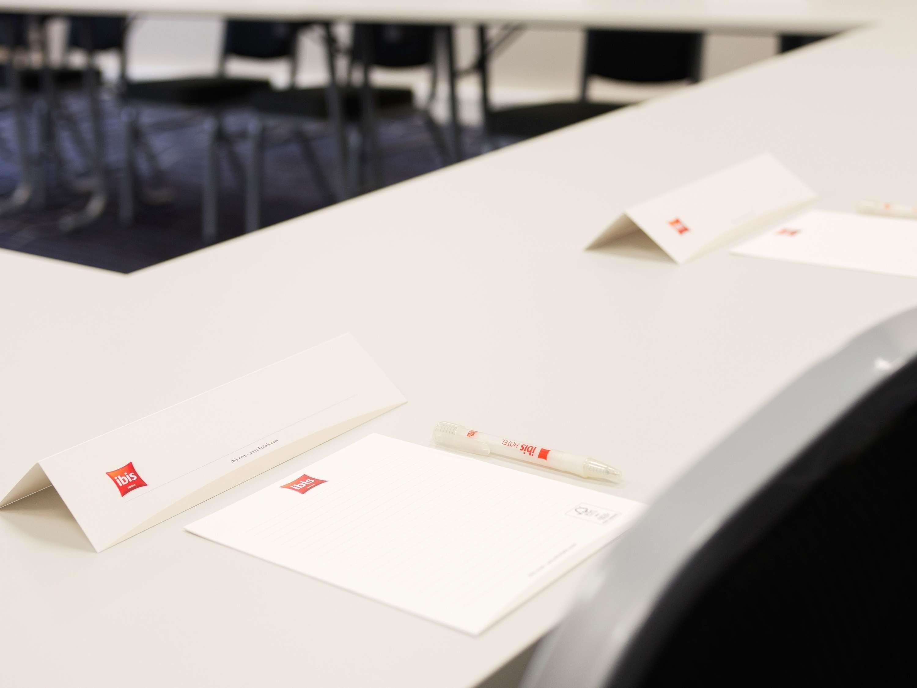 Ein Konferenztisch mit Unterlagen und einem Stift, der eine geschäftliche oder Besprechungssituation andeutet.