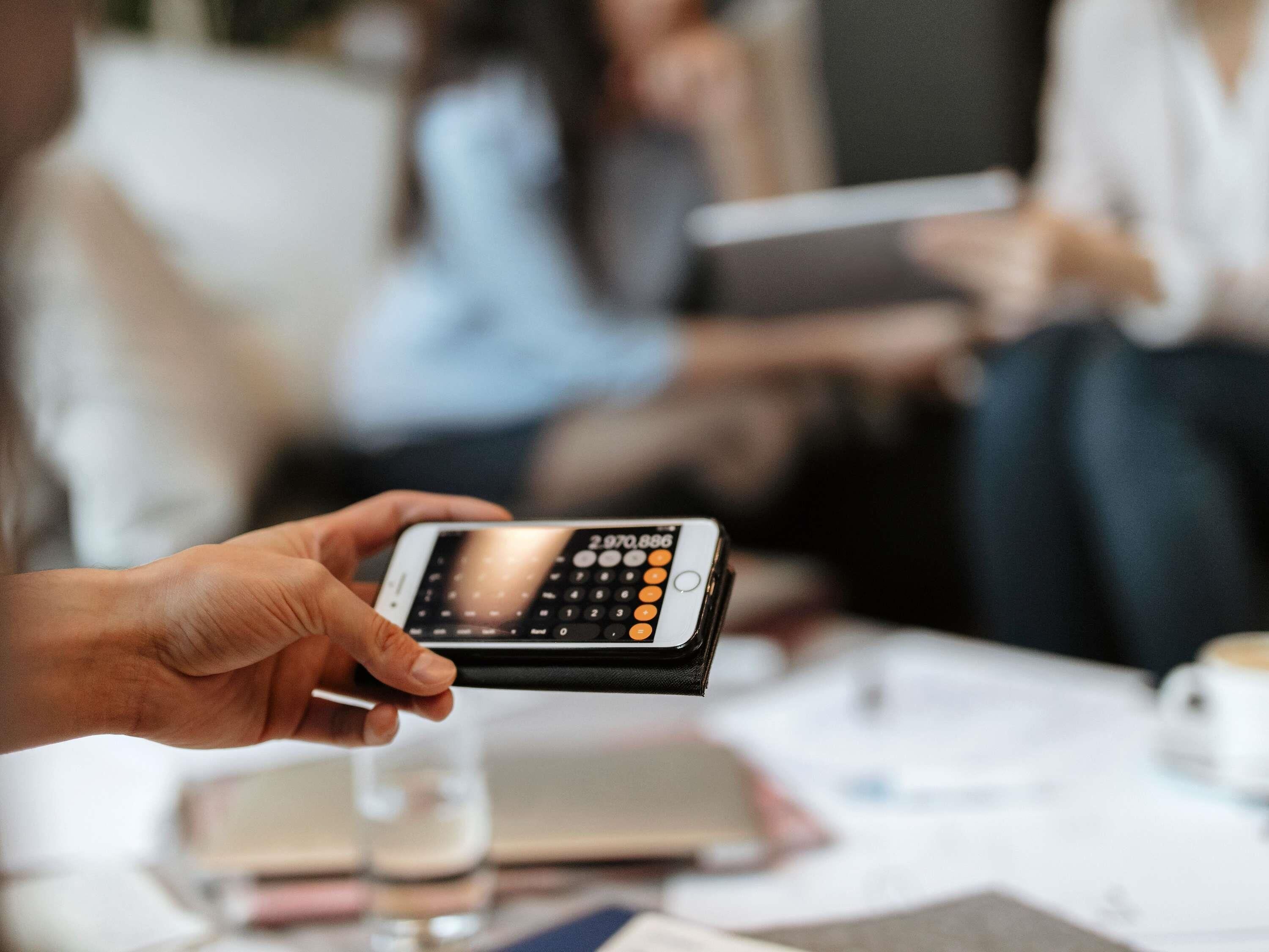 Una persona sosteniendo un teléfono inteligente con teclado numérico, una pantalla pequeña y algunos botones.