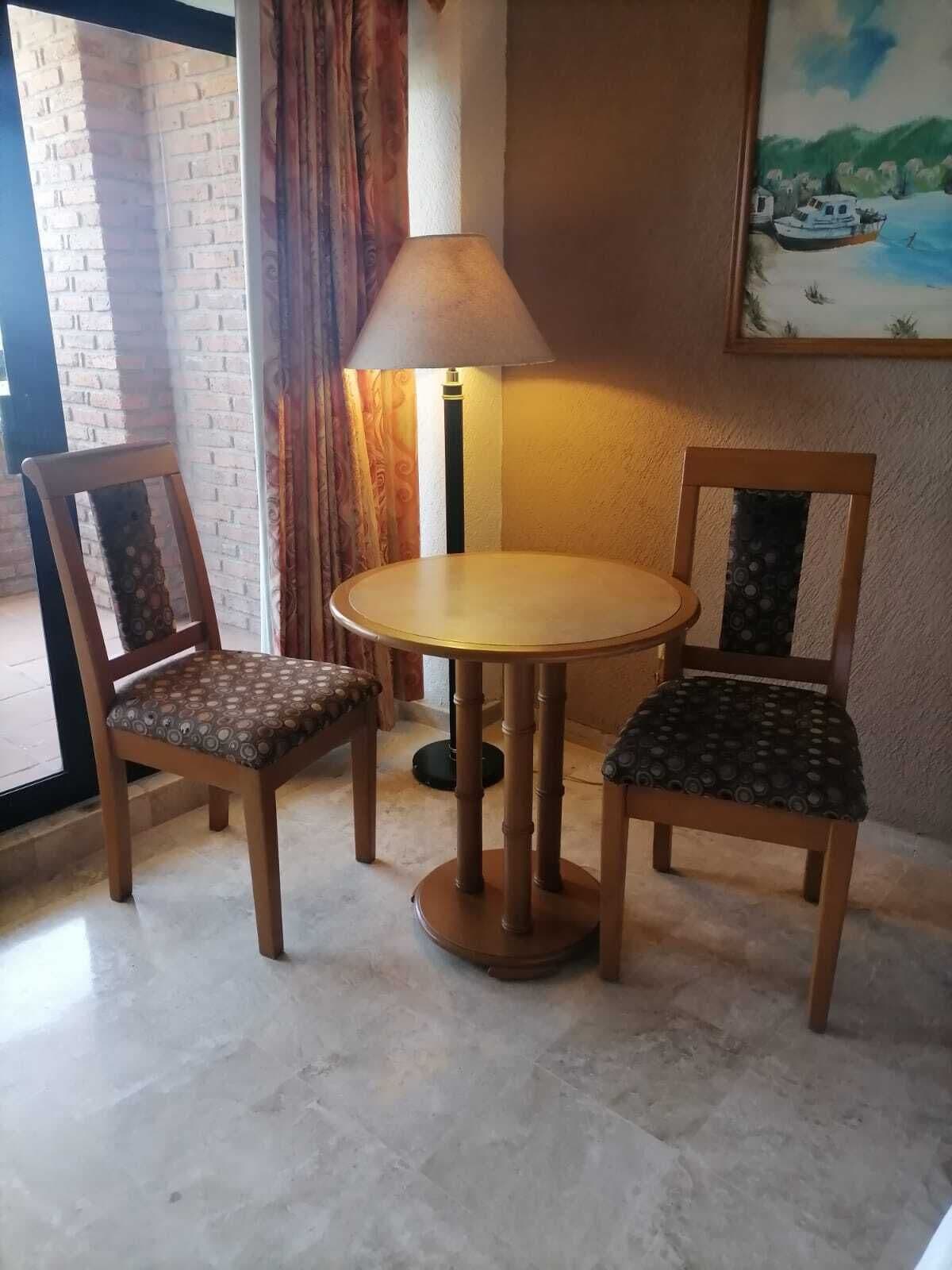 Un coin repas avec une table ronde et deux chaises, une lampe et un tableau au mur.