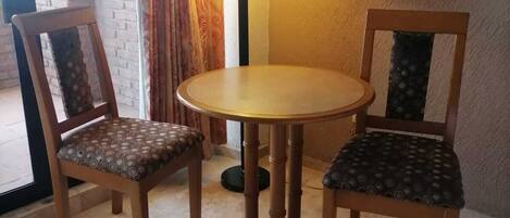 Un comedor con una mesa redonda y dos sillas, una lámpara y un cuadro en la pared.