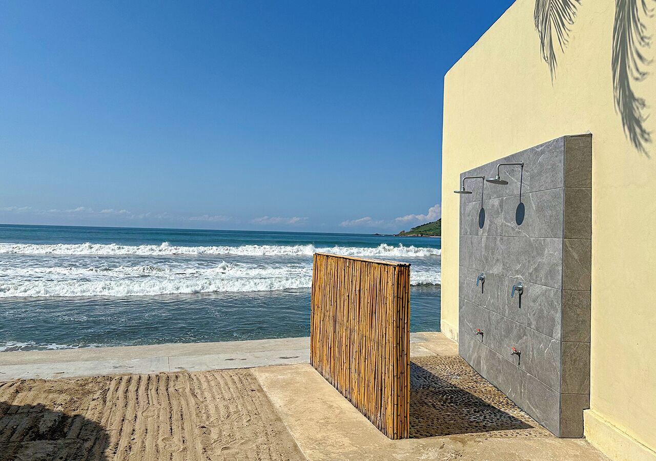 Vista frente a la playa con una estructura de madera y un muro con varios grifos.