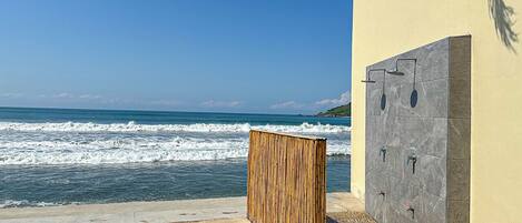 Vista frente a la playa con una estructura de madera y un muro con varios grifos.