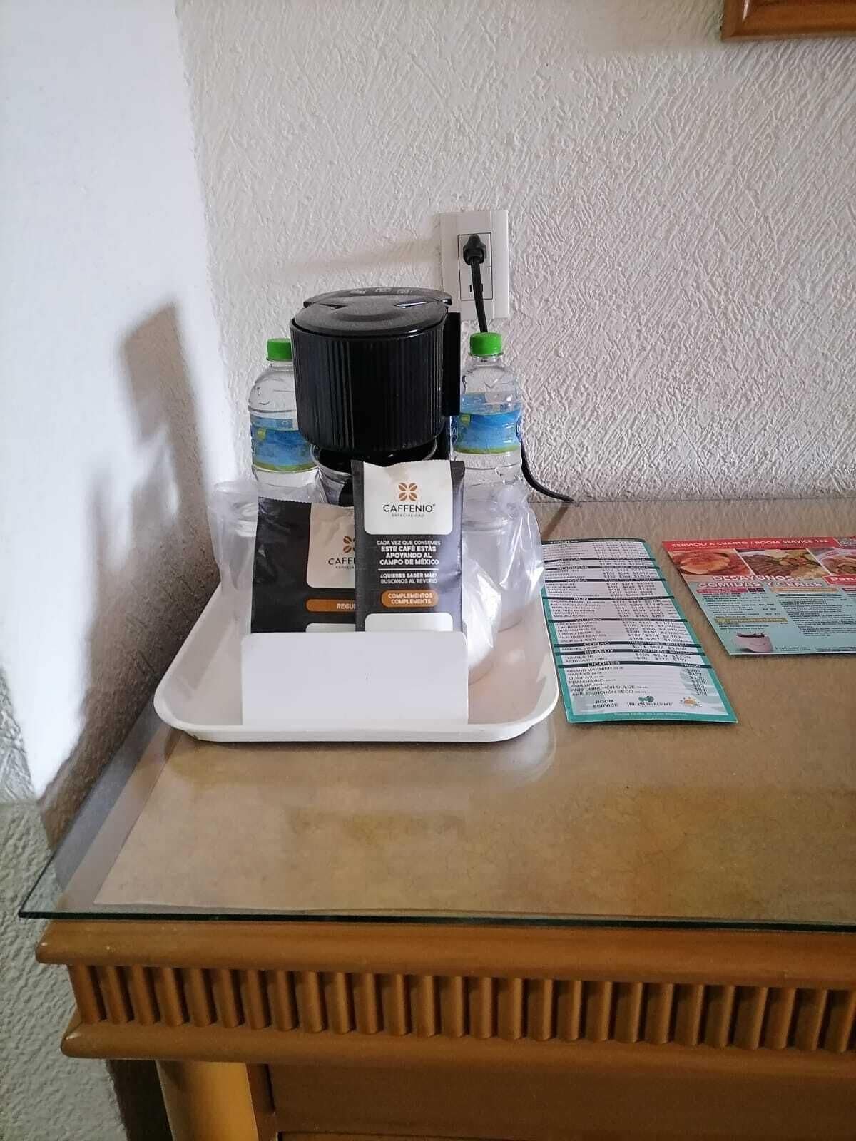 A coffee machine with water bottles and a menu on a table.