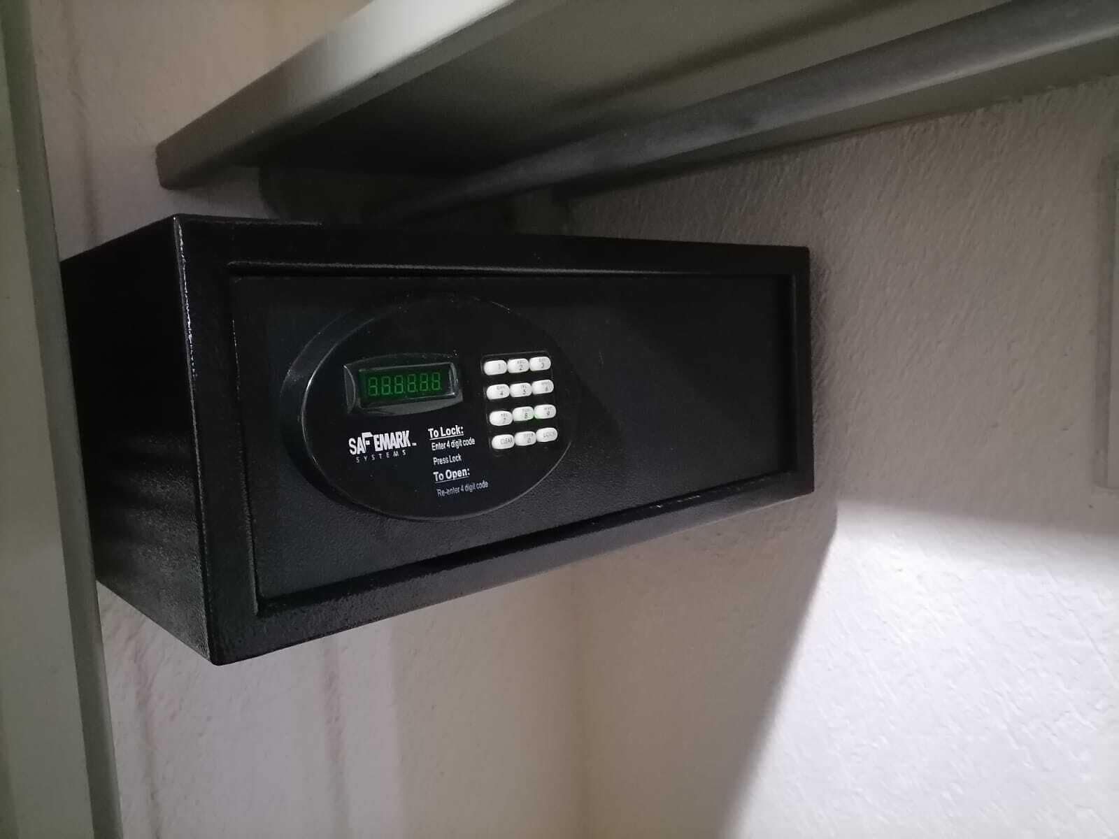 A black electronic lock with a digital display and keypad, mounted on a white wall.