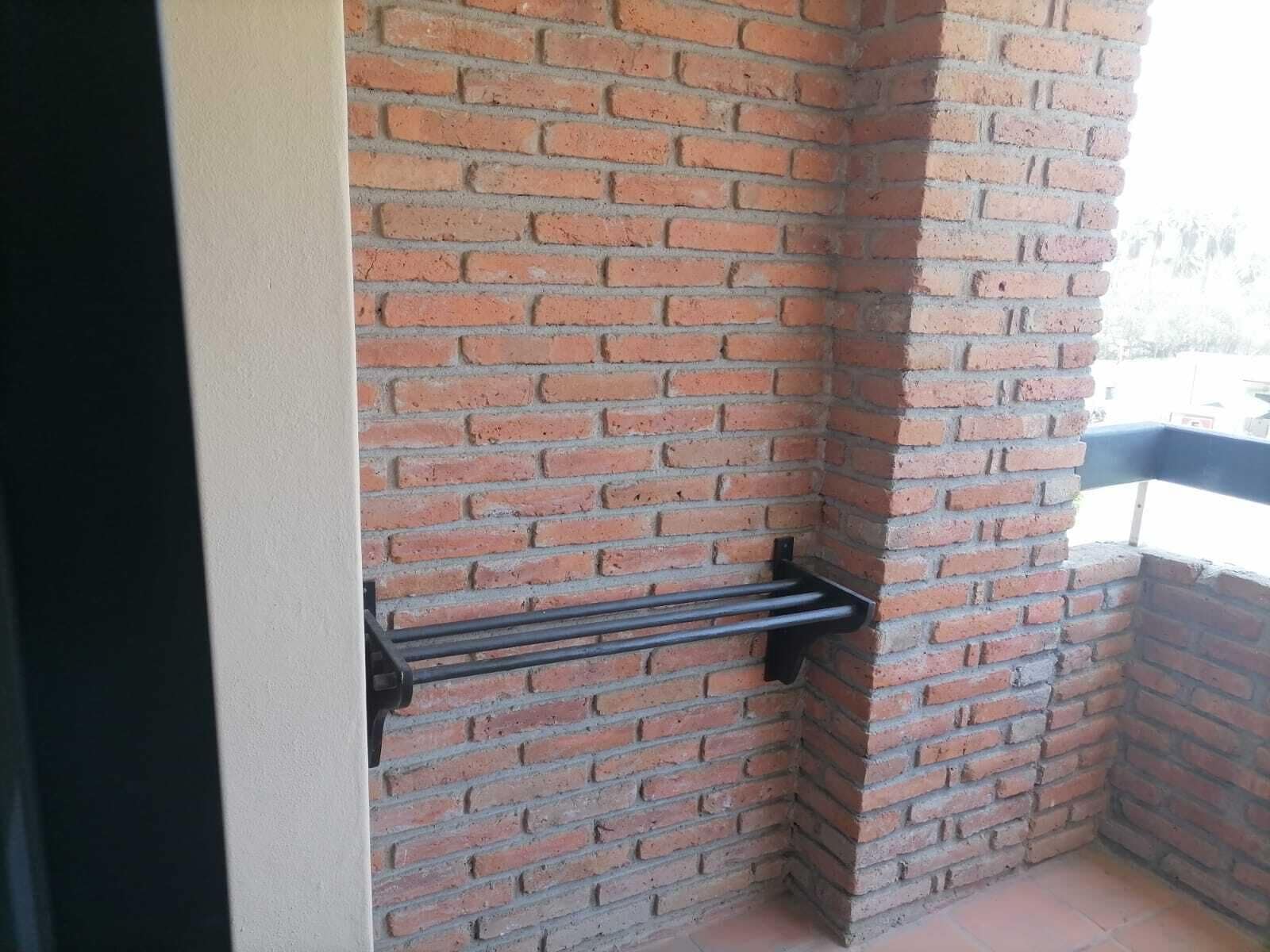 Un coin d'un mur en briques avec un porte-serviettes en métal.