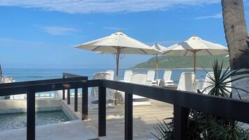 Alberca al aire libre, sombrillas en la alberca y camastros