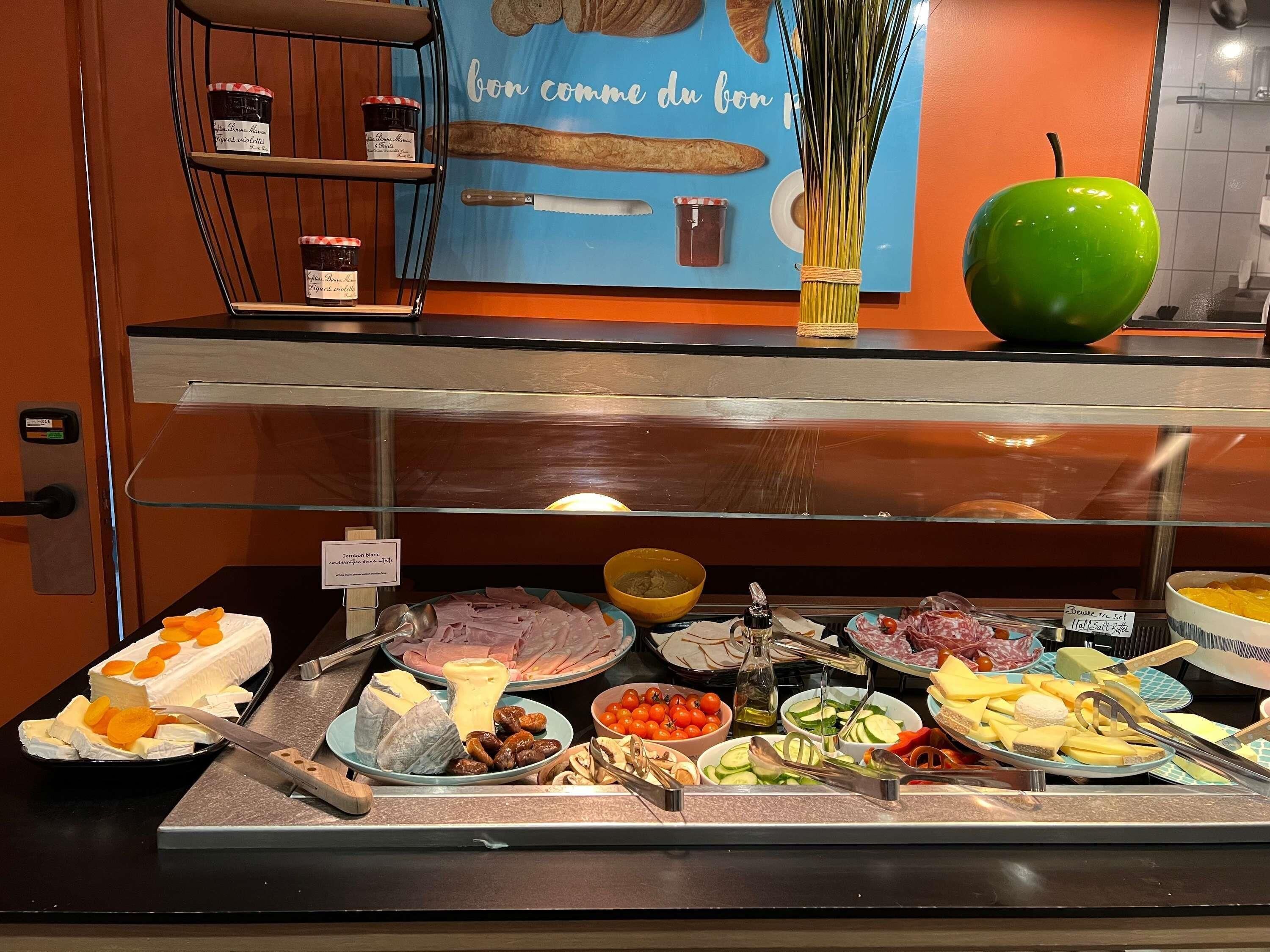 A buffet with various cheeses, meats, and fruits.