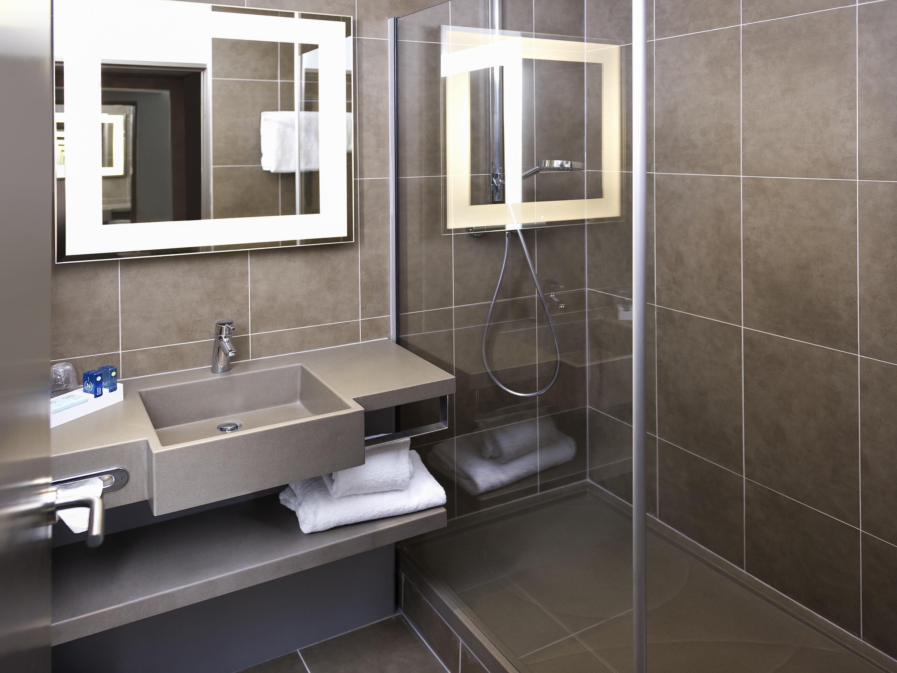 Un bagno moderno con lavandino, specchio e doccia.
