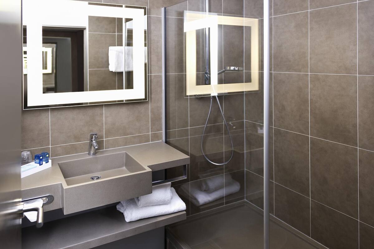 Een moderne badkamer met een wastafel, spiegel en douche.
