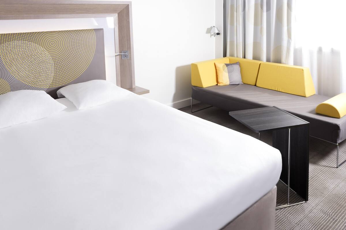 Een moderne hotelkamer met een groot bed, een bank en een kleine tafel.