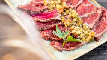 A plate of sliced steak with a herb and vegetable topping.
