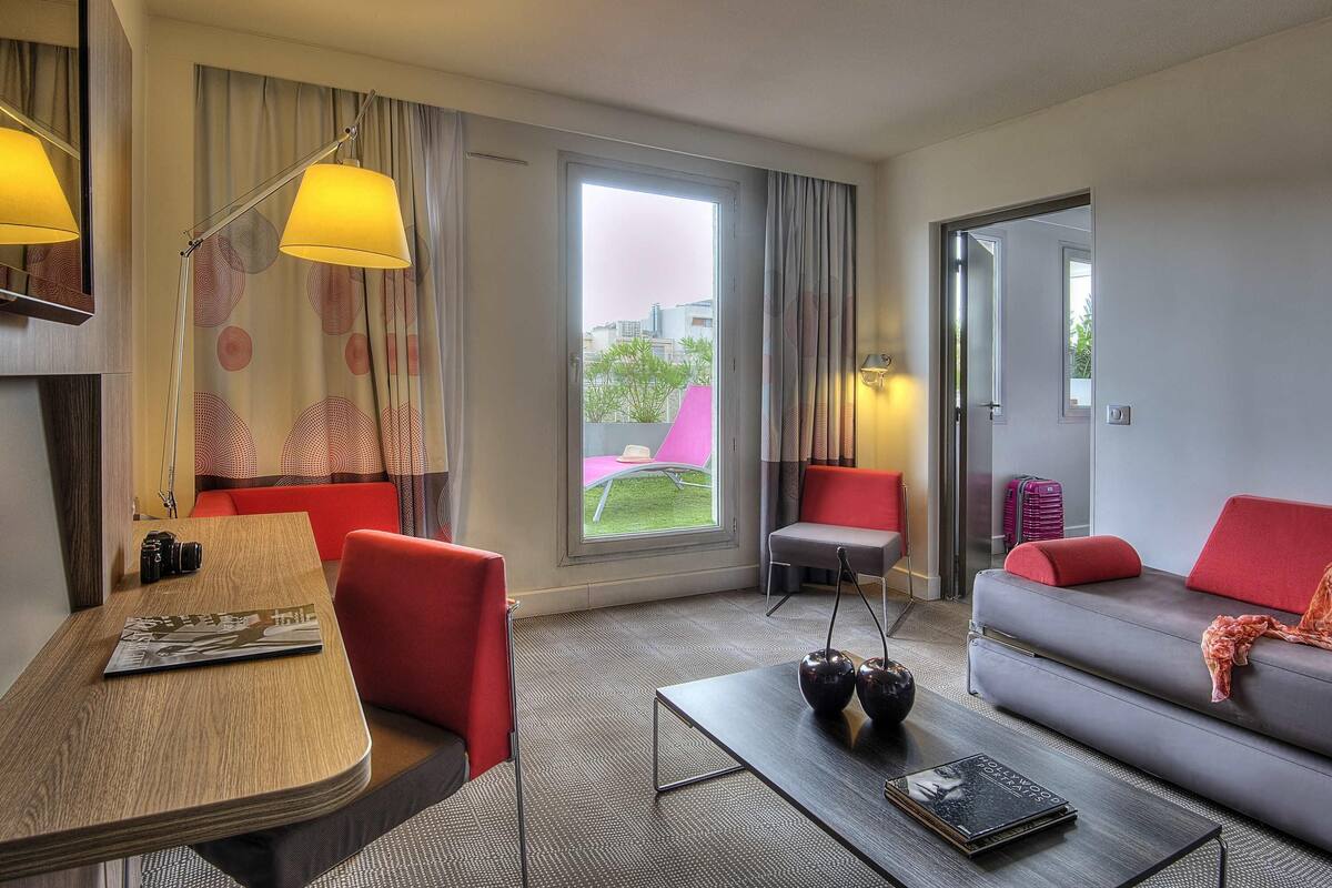 Een moderne hotelkamer met een zithoek, een sofa en een raam met gordijnen.