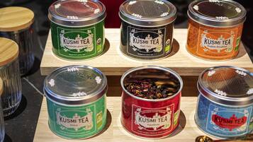Una selezione di barattoli KUSMI TEA esposti su un ripiano in legno.
